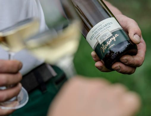 Person die eine Weinflashe von Herzinger hält